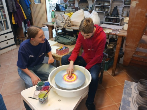 Ein Junge zentriert sich mit Farben auf der Töpferscheibe