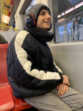 Ein Junge sitzt mit Kopfhörern in der U-Bahn