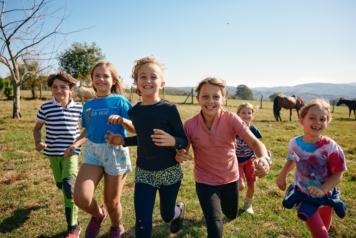 spielende Kinder in der Natur, im Hintergrund Pferde