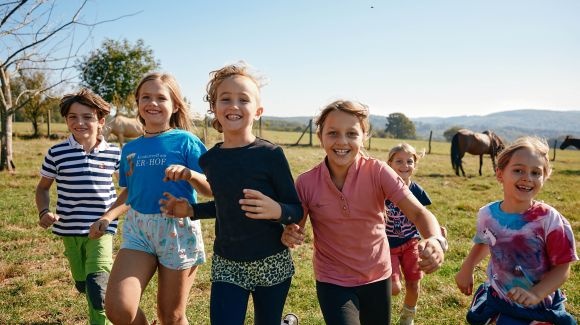 spielende Kinder im Freien, im Hintergrund Pferde