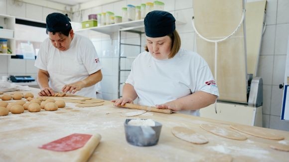 zwei Menschen stehen in einer Backstube und backen Weckerln